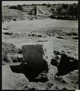 Excavated site at Ayia Irini with a large block of masonry in the foreground and a white tent behind.