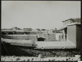 Village view at Ayia Irini with Erik Sjöqvist standing on a balcony among flat-roofed stone houses