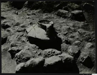 In situ vessel with a wide mouth, set among stones during excavation at Ayia Irini