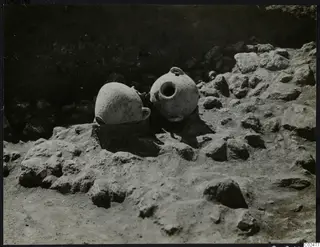 Two pottery vessels with small handles among stones in an excavation at Ayia Irini