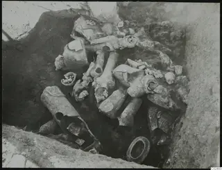 Broken pale ceramic objects lying in situ in an excavated trench at Ayia Irini
