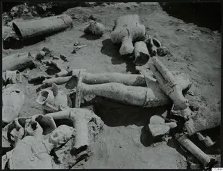 Broken sculpture fragments lying in situ in excavated soil at Ayia Irini