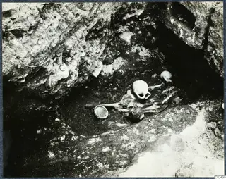 Skeletal remains in situ in a rock-cut hollow during excavation at Enkomi, with a vessel beside them