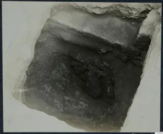 Tomb 17 at Enkomi during excavation, looking down into the chamber at a cluster of dark stones