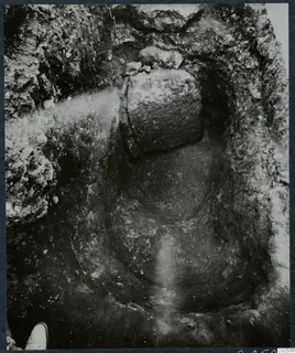 Enkomi excavation: a cut in the ground with large stones at the top and a shoe at the lower left edge.