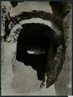 Tomb 3 at Enkomi: opening of a rock-cut tomb chamber seen from its dromos, with stones inside