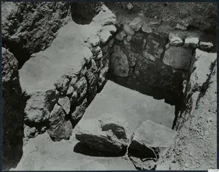 Tomb 5 at Enkomi during excavation: chamber with stone walls and large loose stones on the floor.