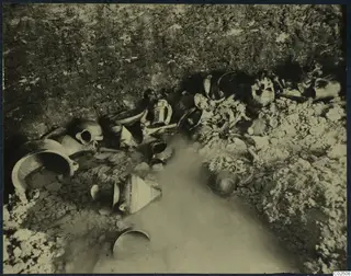 Tomb 2 at Enkomi: tomb chamber during excavation, with pottery vessels, skulls and bones lying in standing water.