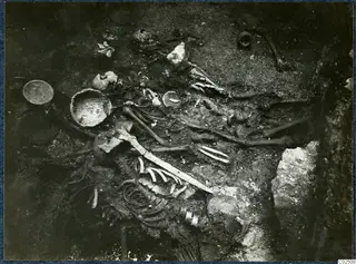 Skeleton and grave goods in situ in Tomb 18 at Enkomi, with bowls, a dish and a long blade-like object