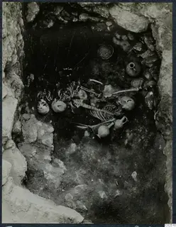 Interior of Tomb 14 at Enkomi, with skeletal remains and pottery vessels lying in the rock-cut chamber.