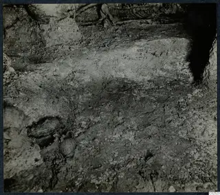 Tomb chamber floor at Enkomi, a dusty, cracked surface with rounded dark forms during excavation