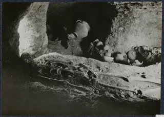 Skeleton and pottery vessels lying in situ in a tomb chamber at Ayios Iakovos during excavation