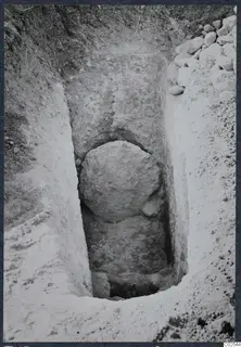Excavation trench at Ayios Iakovos with a large rounded stone set against the cut face and a heap of stones at the edge