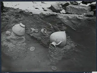 Pottery jugs and bowls in situ during excavation at Marion, Tomb 83
