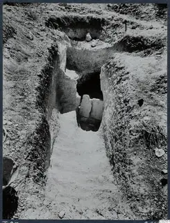 Sloping passage cut into earth leading to the entrance of Tomb 87 at Marion, with stone slabs at the opening.