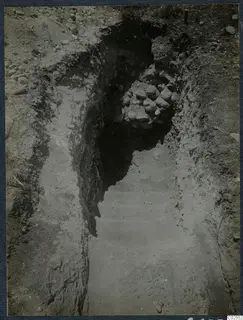 Excavation cutting at Marion, T.92, sloping down toward a heap of stones at the far end, with grass and stones on the ground