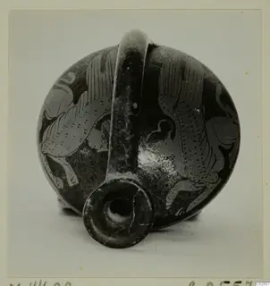 Dark-surfaced vessel with a strap handle and pale painted figures, mouth facing the camera