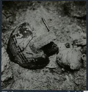 Broken decorated pottery vessel and a second vessel lying in sandy soil, Tomb 18 at Enkomi