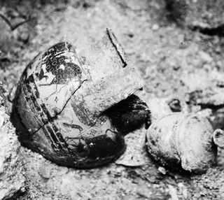 Painted vessel and a rusted metal object lying in sandy soil, Tomb 18 at Enkomi