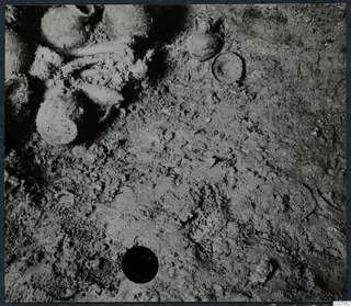 Several rounded vessels lying in excavated soil in Tomb 19 at Enkomi, during excavation