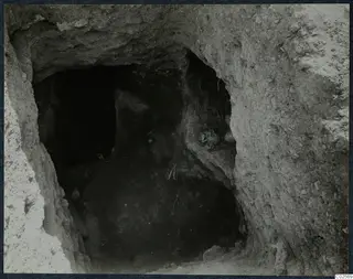 Tomb 19 at Enkomi: view through the excavated opening into the tomb chamber, with objects against the right wall.