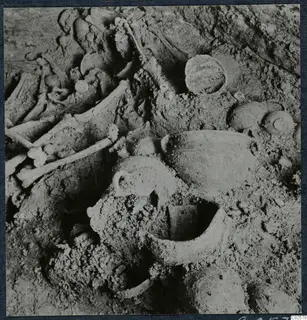 Tomb 19 at Enkomi: bones and pottery vessels lying in soil inside the tomb chamber during excavation.