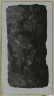 Dark cylindrical seal, photographed on a card mount, with faint markings across its surface