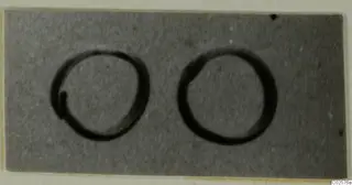 Two rings lying side by side on a grey card, shown as dark circular outlines