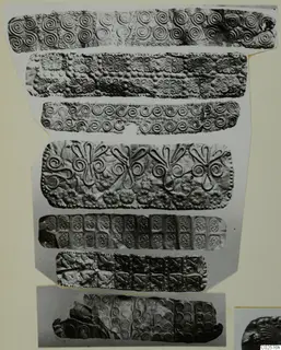 Seven strips of embossed thin metal with spiral, scroll, rosette and bird patterns, laid out on a cream card