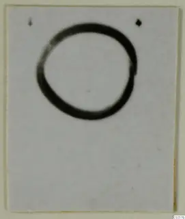 Blurred photograph of a ring-shaped object on a pale card background