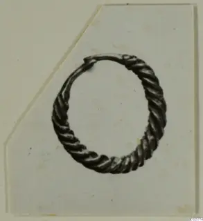 Twisted-wire ring earring from Enkomi, shown on a white card with one corner cut away