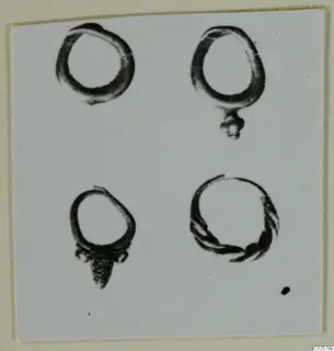 Four rings on a plain card, two of them with small hanging attachments