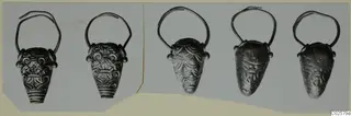 Five gold pendants with wire loops and embossed decoration, arranged in a row on a card mount