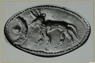 Oval object with a beaded rim and a raised animal design, photographed flat on a pale background.