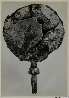 Corroded disc-shaped mirror in broken pieces, with a standing figure forming its handle, from Enkomi