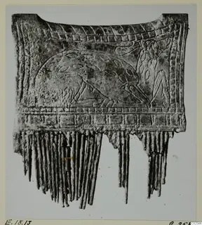 Carved bone object from Enkomi with relief decoration and a fringe of narrow strips along its lower edge.