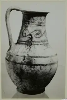 Pottery tankard from Enkomi with a strap handle, painted bands, zigzags and a looping motif on the neck.