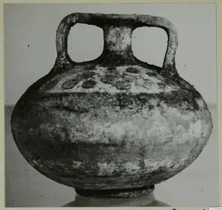 Round, squat vessel with two strap handles and a short neck, photographed from the front against a plain backdrop.