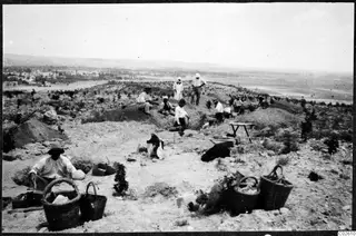 Workers digging on the Idalion acropolis, with woven baskets in the foreground and a town and plain below the hill