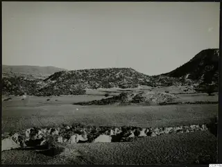 Necropolis hill at Palaeoskoutella seen from the south across a flat, cultivated plain.