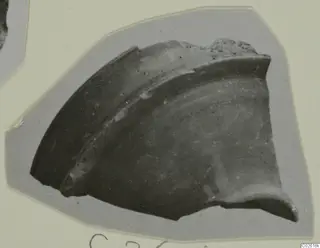 Pottery sherd, a curved rim fragment with a raised band, mounted on grey card