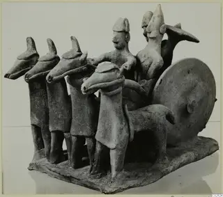 Terracotta model of a chariot drawn by four horse-headed animals, with two figures riding in it
