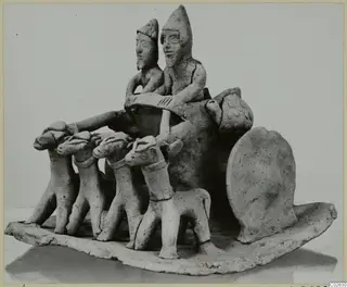 Unglazed clay group of two figures on a cart drawn by four animals, set on an oval base