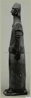 Terracotta Proto-Cypriote II, a tall standing figure seen in profile facing left, in a cap and long robe.