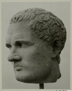 Carved stone head of a man with short curly hair, shown on a thin rod stand.
