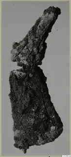 Heavily corroded iron object from Marion, photographed upright against a plain grey background