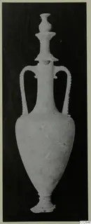 Tall pale stone vessel with two handles and a ribbed stopper, photographed upright on a dark background