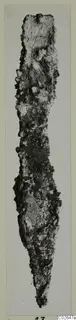 Corroded metal tool from Marion, long and narrow, tapering to a point at the lower end