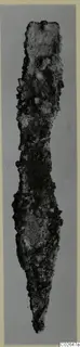 Corroded iron tool with a pointed tip, photographed against a grey backdrop