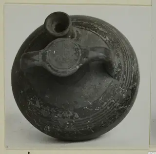 Pottery bowl-jar from Ayios Iakovos with a short neck, a flat lug and loop handles, and bands of concentric lines on its dark surface